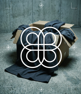 Basico Branco garments spilling from cardboard box against concrete floor with brand logo overlay. 