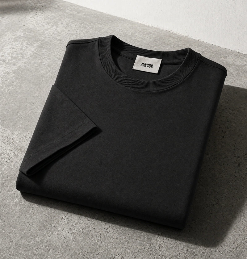 Black crewneck sweatshirt folded on a gray concrete surface with a white wall in the background.