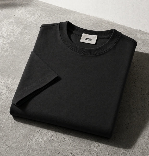 Black crewneck sweatshirt folded on a gray concrete surface with a white wall in the background.