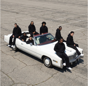 Basico Branco black hoodies worn by models on a white convertible.